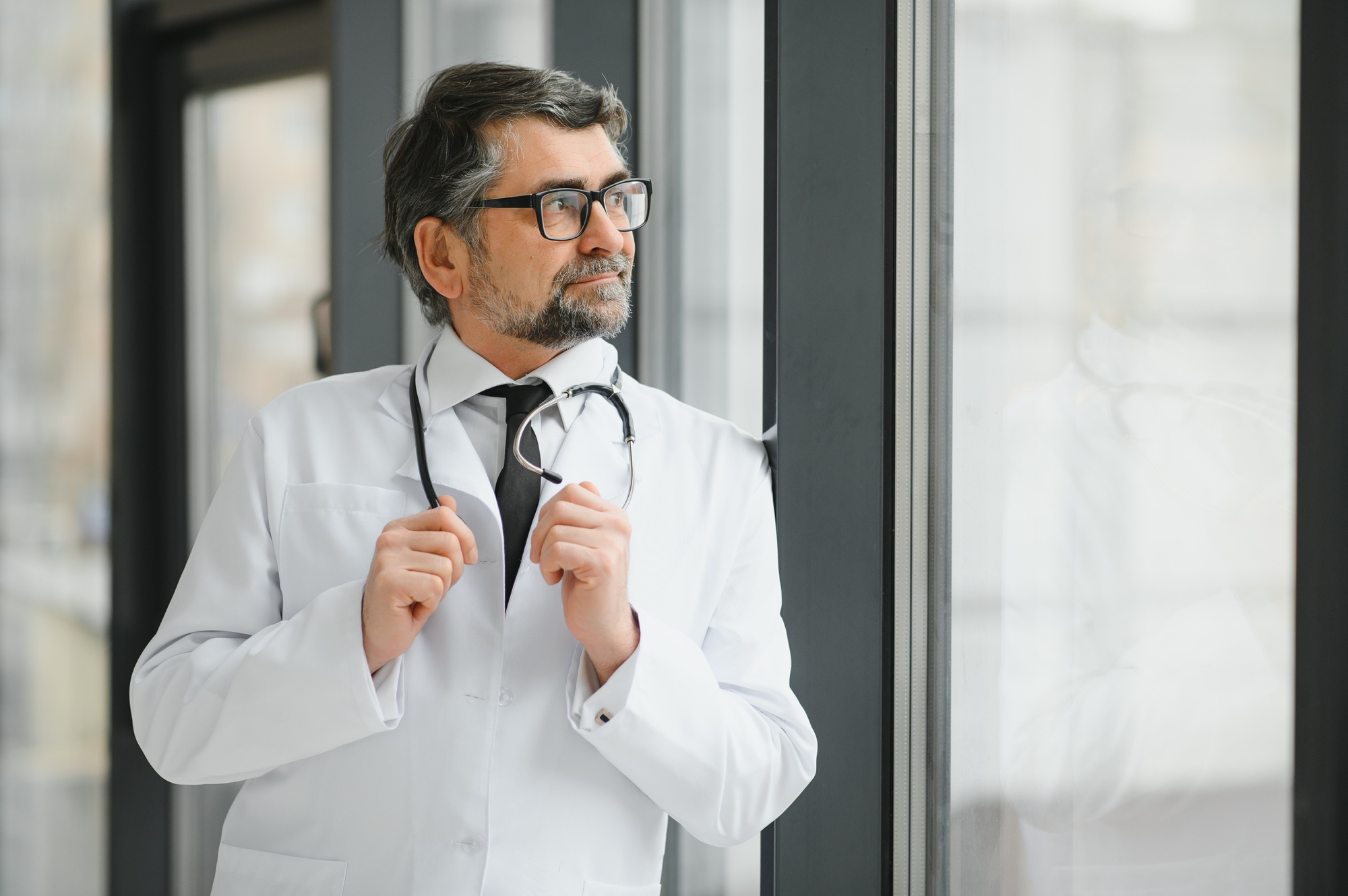 Happy confident bearded old professional doctor standing.